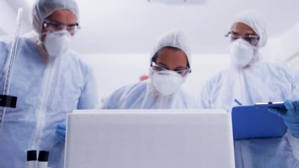 Team of researcher in a modern laboratory opening refrigerator box and taking notes — Stock Video