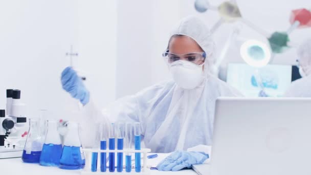 Cientista feminina em laboratório moderno vestindo um equipamento de macacão coletando amostras — Vídeo de Stock