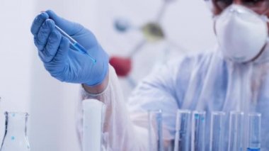 Pipet kullanarak mavi reaktif döken tulum koruma ekipmanları ile modern laboratuvarda Bilim adamı