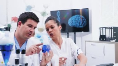 Bir alıcı bir sigara mavi sıvı tutan genç bilim adamı ekibi