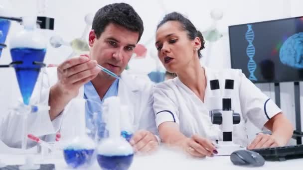 Equipo de químicos en el laboratorio estudiando un líquido azul humeante — Vídeos de Stock