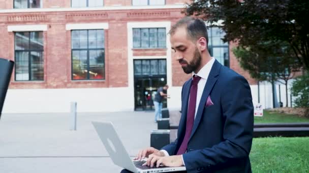 Joven hombre de negocios que trabaja en el portátil en un distrito de negocios, cerca de cámara lenta — Vídeos de Stock