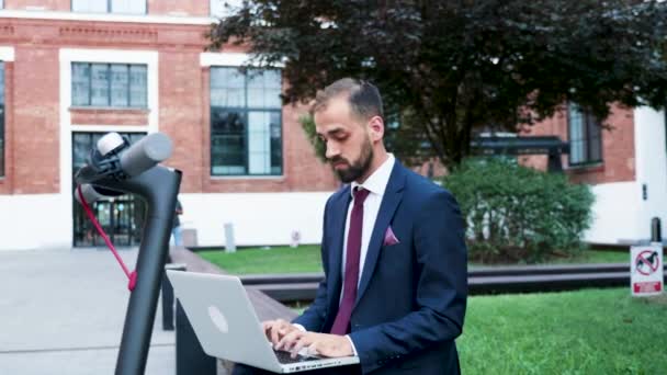 Zelfverzekerde zakenman buiten werken op de computer, zoom in slow motion — Stockvideo