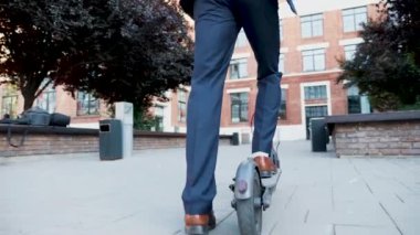 İşe gitmek için elektrikli scooter kullanan yöneticinin çekimini takip edin