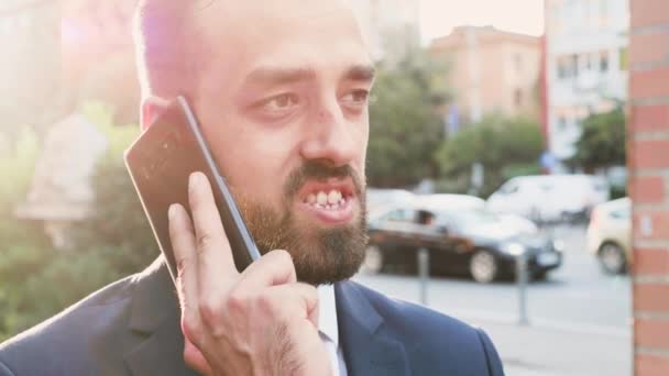 Portrét obchodní osoby, která mluvila po telefonu se sluncem za sebou — Stock video