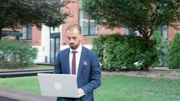 Gestionnaire en costume formel tapant sur l'ordinateur portable, travaillant en plein air dans la ville — Video