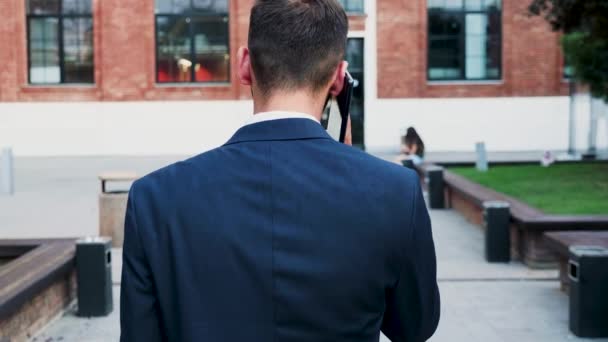 Вид ззаду бізнесмена, який розмовляє по телефону, повільний рух — стокове відео