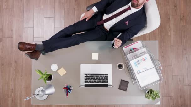 Vista superior del exitoso hombre de negocios con sus pies en el escritorio — Vídeos de Stock