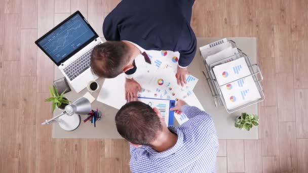 Vista superior de dos hombres de negocios revisando gráficos de diferentes archivos — Vídeo de stock