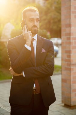 Gün batımında dışarıda telefonla konuşan işadamı