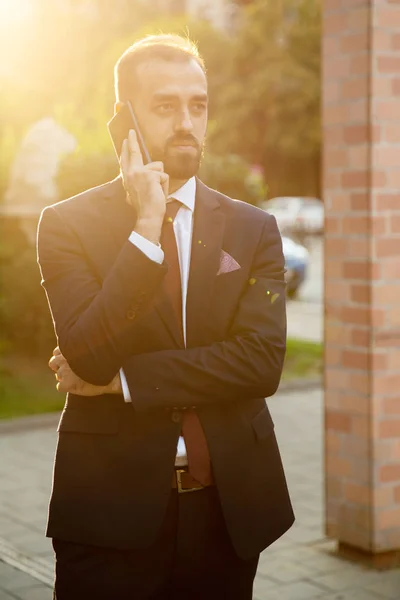 Empresário falando ao telefone lá fora ao pôr do sol — Fotografia de Stock