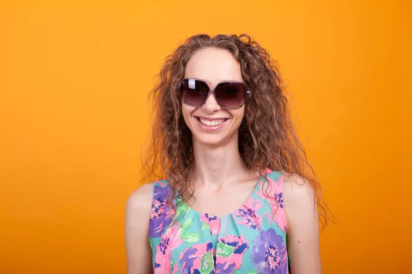 Portrait de jeune femme souriante et portant des lunettes de soleil en studio — Photo