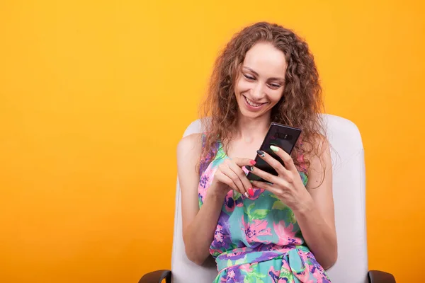Onun akıllı telefon kullanarak gülümseyen kıvırcık saçlı çekici kadın — Stok fotoğraf