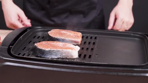 Шеф-повар, курирующий свежий лосось, жарящийся на сковороде — стоковое видео