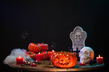 Cadılar Bayramı kutlamalarında ürpertici bir kafatası ile ahşap bir masa üzerinde oturan oyulmuş korkunç kabak