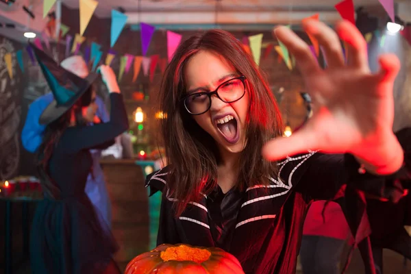 Menina com uma abóbora para halloween gritando e estendendo a mão para a câmera — Fotografia de Stock