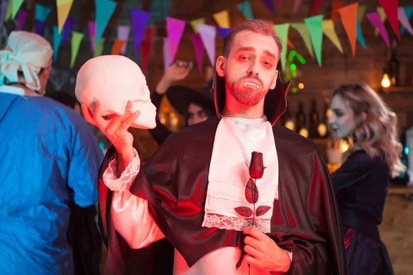 Aantrekkelijke man gekleed als vampier met een menselijke schedel op Halloween Party — Stockfoto