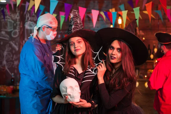 Médico louco com sangue atrás de duas bruxas bonitas na festa de Halloween — Fotografia de Stock