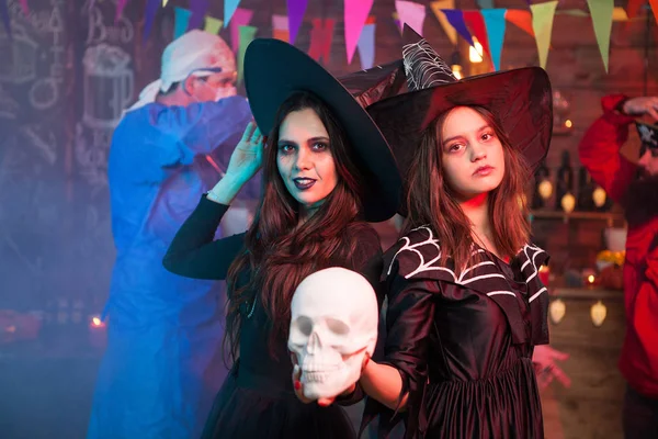 Twee heksen op een Halloween viering houden van een menselijke schedel — Stockfoto