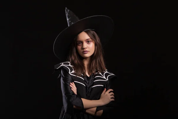 Girl doing dark spells with her arms crossed and serious expression at halloween carnival