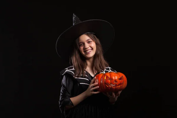 Little girl in a witch costume doing witchcraft on a scary pumpkin — Stock Photo, Image