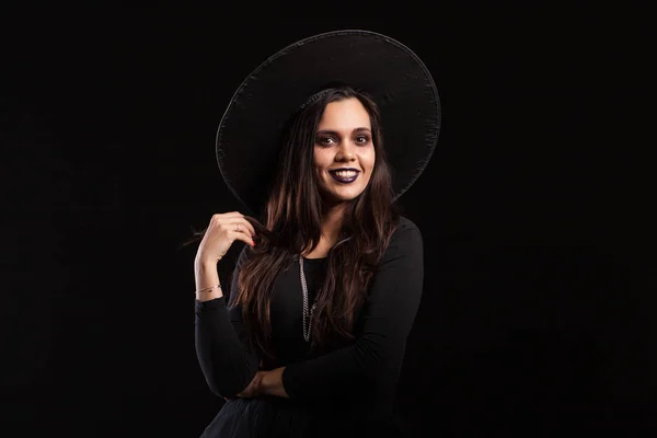 Hermosa y aterradora bruja sosteniendo su cabello sobre fondo negro — Foto de Stock