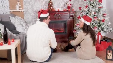 Inlove çift Noel dekore edilmiş odada bir şömine önünde katta oturan