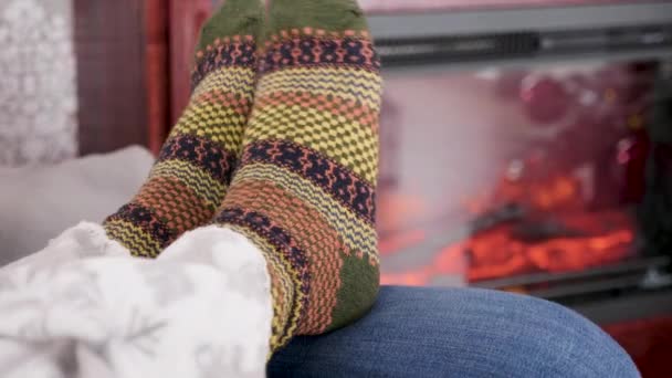 Женщина ноги в теплых шерстяных носках рядом с горящим камином — стоковое видео