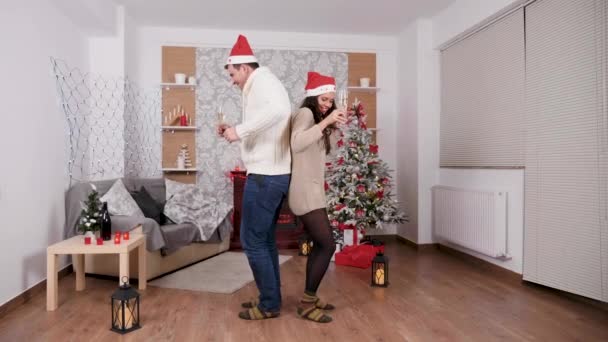 Coppia caucasica che balla con bicchieri di champagne in mano, stanza decorata di Natale — Video Stock