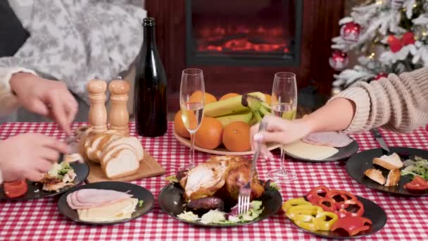 Paar klappert Champagner und genießt ein Weihnachtsessen vor dem Kamin — Stockvideo