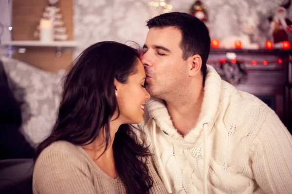 Hermosa joven esposa besada en su frente por su marido cariñoso en Navidad —  Fotos de Stock
