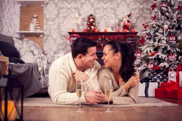 Young man telling a story to his wife laying down on the floor celebrating christmas — Stock Photo, Image