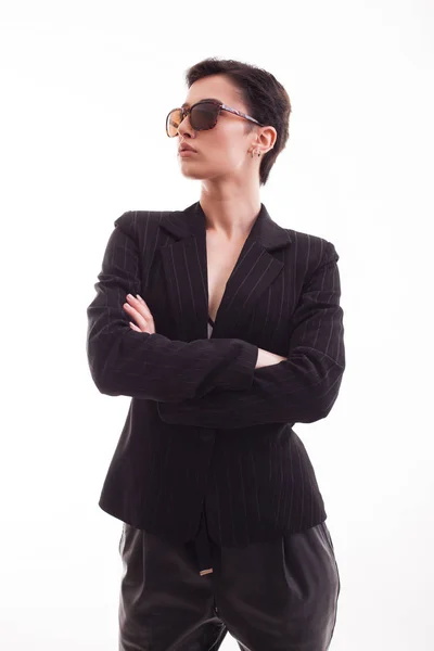 Atractiva modelo de moda posando en chaqueta negra con gafas de sol sobre fondo blanco en estudio — Foto de Stock