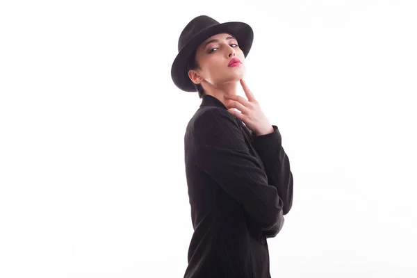 Caucásico belleza posando con confianza delante de la cámara en el estudio con un sombrero retro y elegante chaqueta negra sobre fondo blanco — Foto de Stock