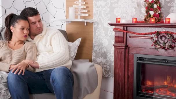 Happy inlove couple looking at the fireplace sitting on the sofa — Stock Video