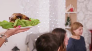 Arka planda Noel ağacı ile Noel masası etrafında büyük aile toplanması