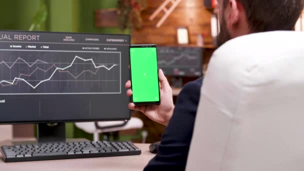 Empresario en el lugar de trabajo moderno que sostiene el teléfono con pantalla verde — Vídeos de Stock