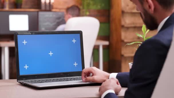 Молодой бородатый бизнесмен печатает на ноутбуке с зеленым экраном — стоковое видео