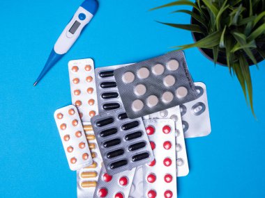 Termometresi olan üst manzara ve mavi arka planda çok renkli haplarla su toplaması.