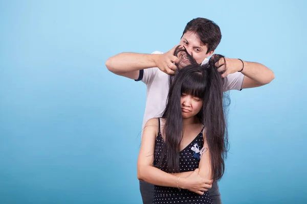 Расстроенная азиатская девушка и кавказский парень дразнят ее — стоковое фото