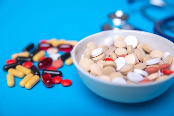 Cierre con un tazón de pastillas y muchas píldoras de diferentes colores — Foto de Stock
