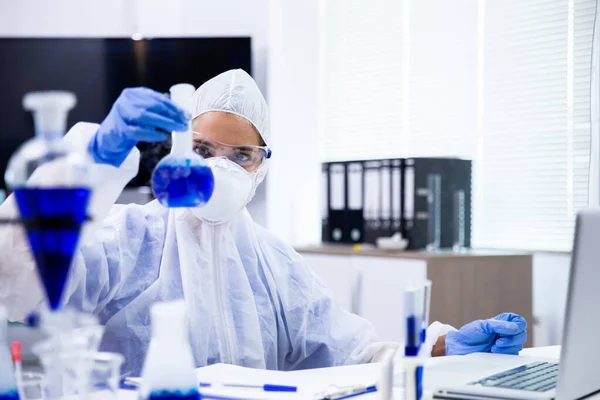 Científico mira un tubo con un líquido azul —  Fotos de Stock