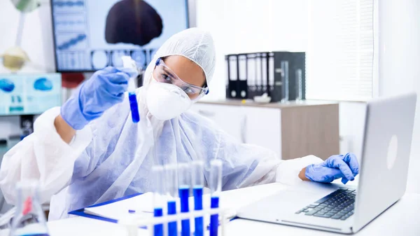 Kaukasischer Wissenschaftler analysiert Röhre und macht sich Notizen auf Laptop — Stockfoto