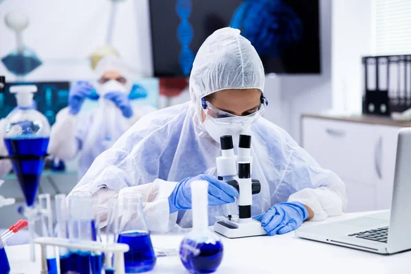Vrouwelijke wetenschapper kijkt door een microscoop in onderzoekslaboratorium — Stockfoto