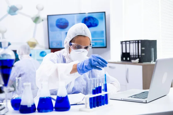 Científica enfocada tomando una muestra de solución azul del tubo de ensayo — Foto de Stock