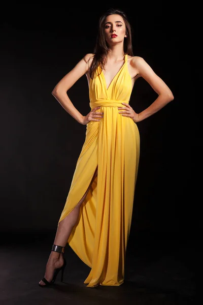 Stylish brunette female wearing yellow fashion dress on black background — Stock Photo, Image