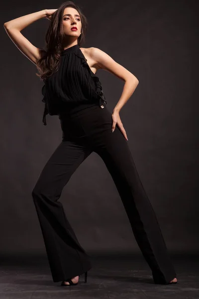 Красивая модель в черных штанах позирует в студии — стоковое фото