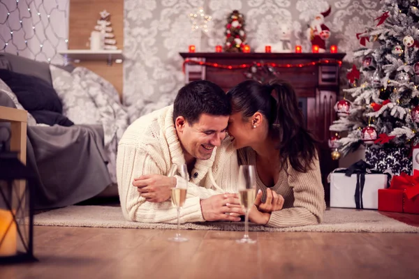 Joven esposa susurrando algo en su oído marido celebrando la Navidad —  Fotos de Stock