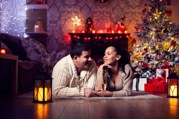 Foto de una joven pareja descansando junto al fireplaec en la sala de Navidad —  Fotos de Stock