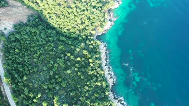 Drone volando sobre la carretera cerca de la costa rocosa con agua de mar turquesa — Vídeo de stock